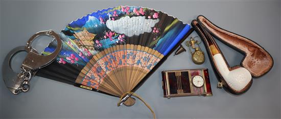 A minaudiere with timepiece, a meerschaum pipe in case, pair of handcuffs and key, a Chinese fan, a miniature scent bottle and a masoni